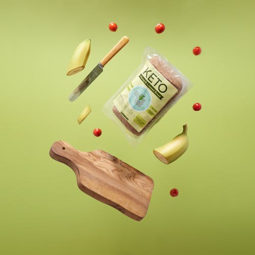 Free Keto Bread, Wooden Chopping Board With Knife and Fork, Sliced Banana and Cherry Tomatoes  Stock Photo