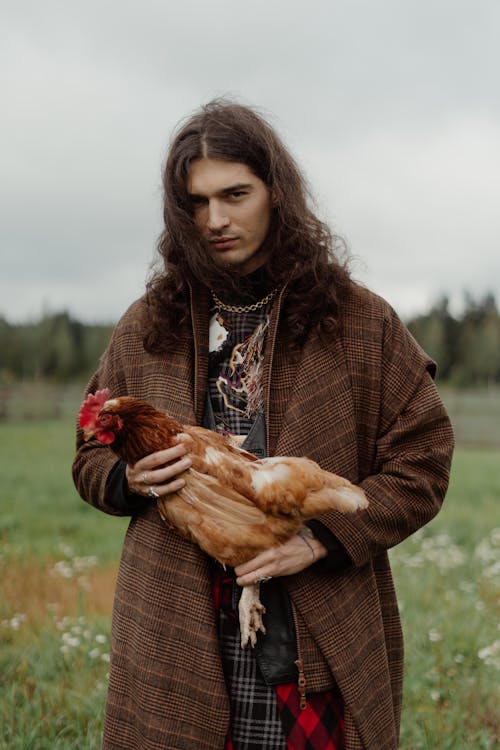 Portrait of a Man with Long Hair Holding a Chicken