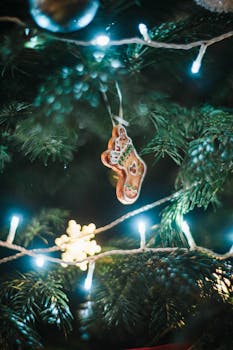 Festive gingerbread ornament hanging on a Christmas tree with decorative lights.