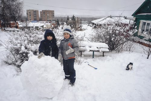 Two Kids Standing on a Snow-Covered Field