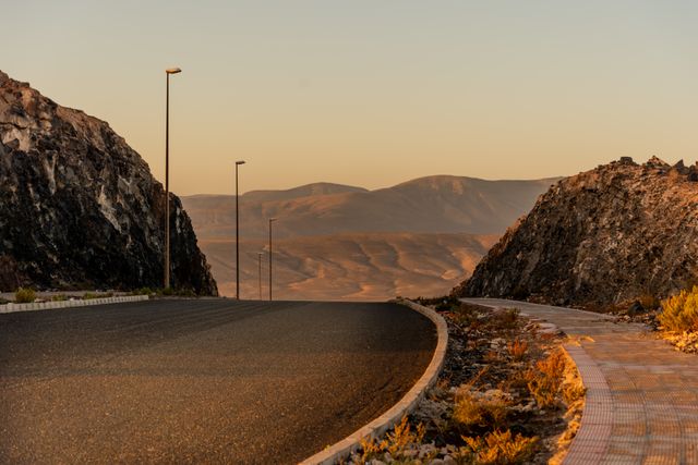 Empty highway curving toward desert mountains at sunset — photo by silviu rarau on Pexels