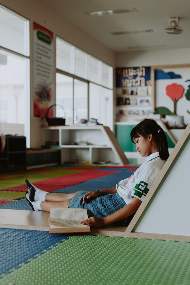 Thai Girl In School Uniform Sitting On Ground Reading Book