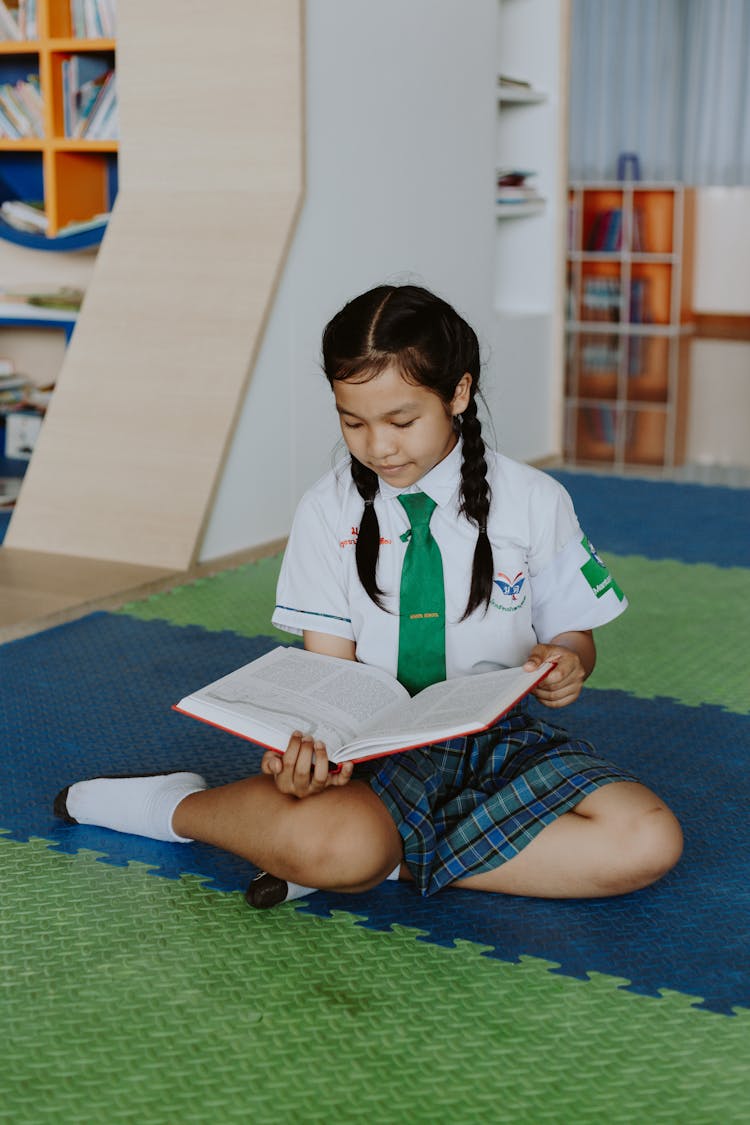 Thai School Girl Sitting On Ground Reading Book