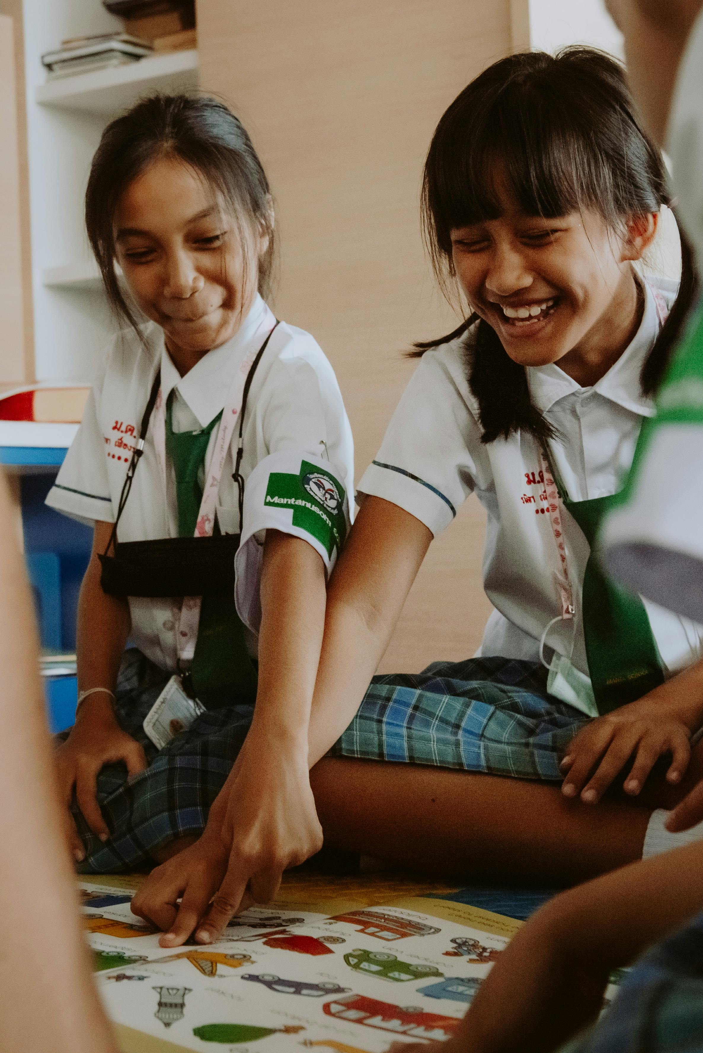 thai school girls in uniforms pointing at picture