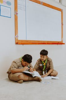 Two boys in uniform studying in a classroom, fostering teamwork and education.