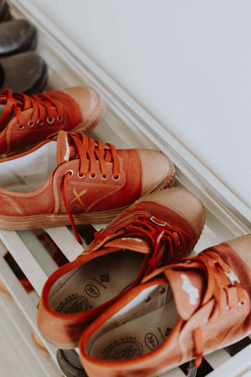 Red sneakers lined up neatly on a white shoe rack in a small entryway