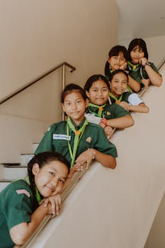 A group of cheerful students in uniforms posing on a stairway indoors, showcasing education and togetherness.