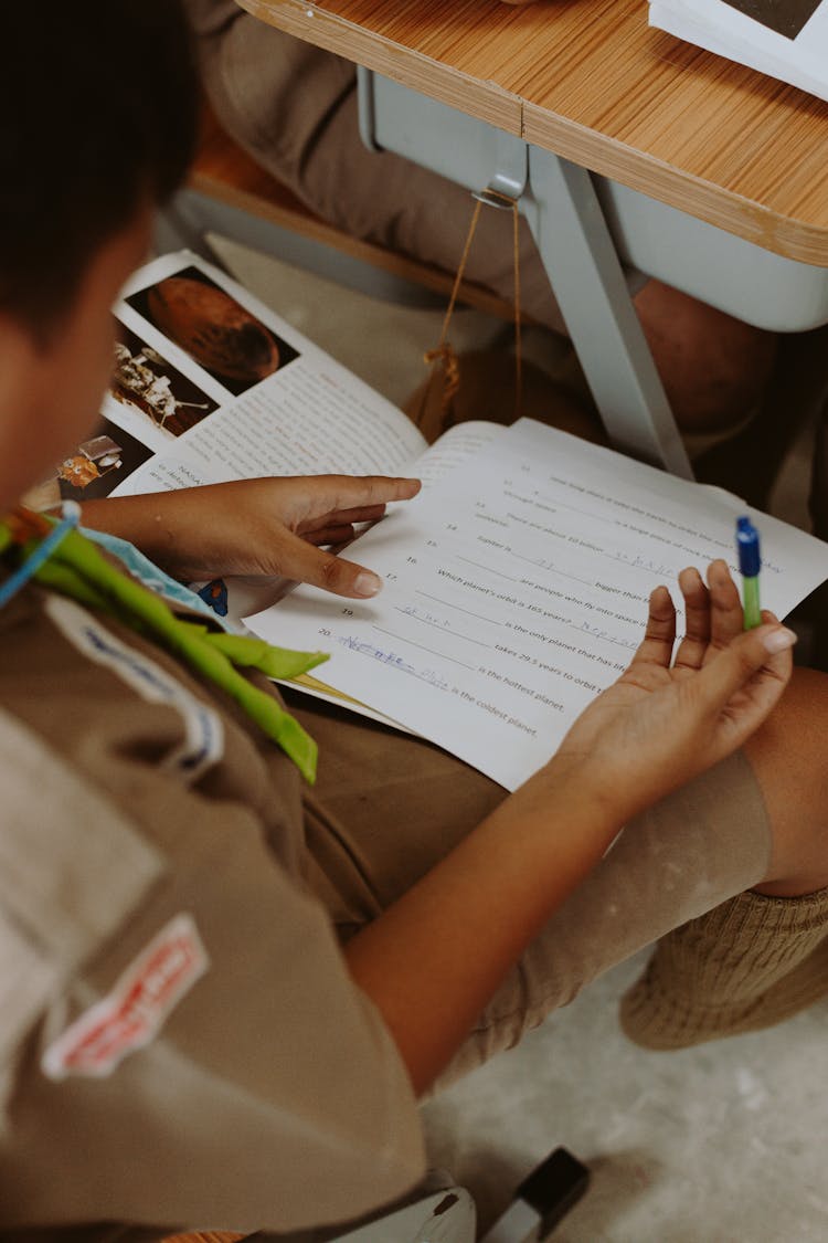 A Kid Holding A Pen And Test Paper 