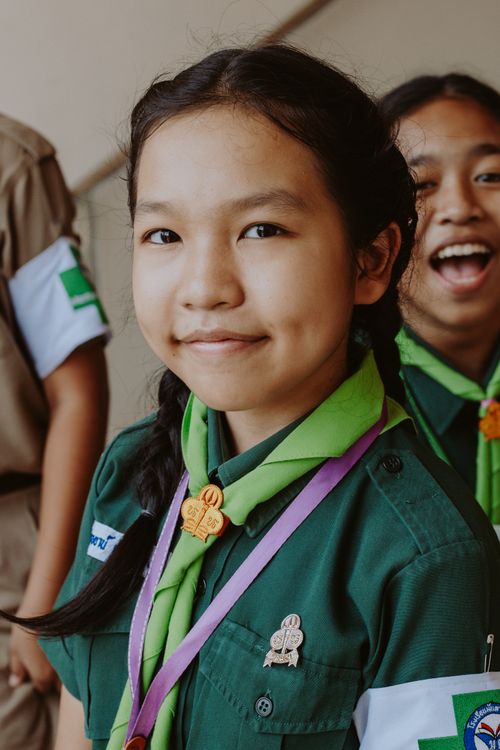 Free Portrait of a smiling girl scout in a green uniform and scarf, representing youth and education. Stock Photo