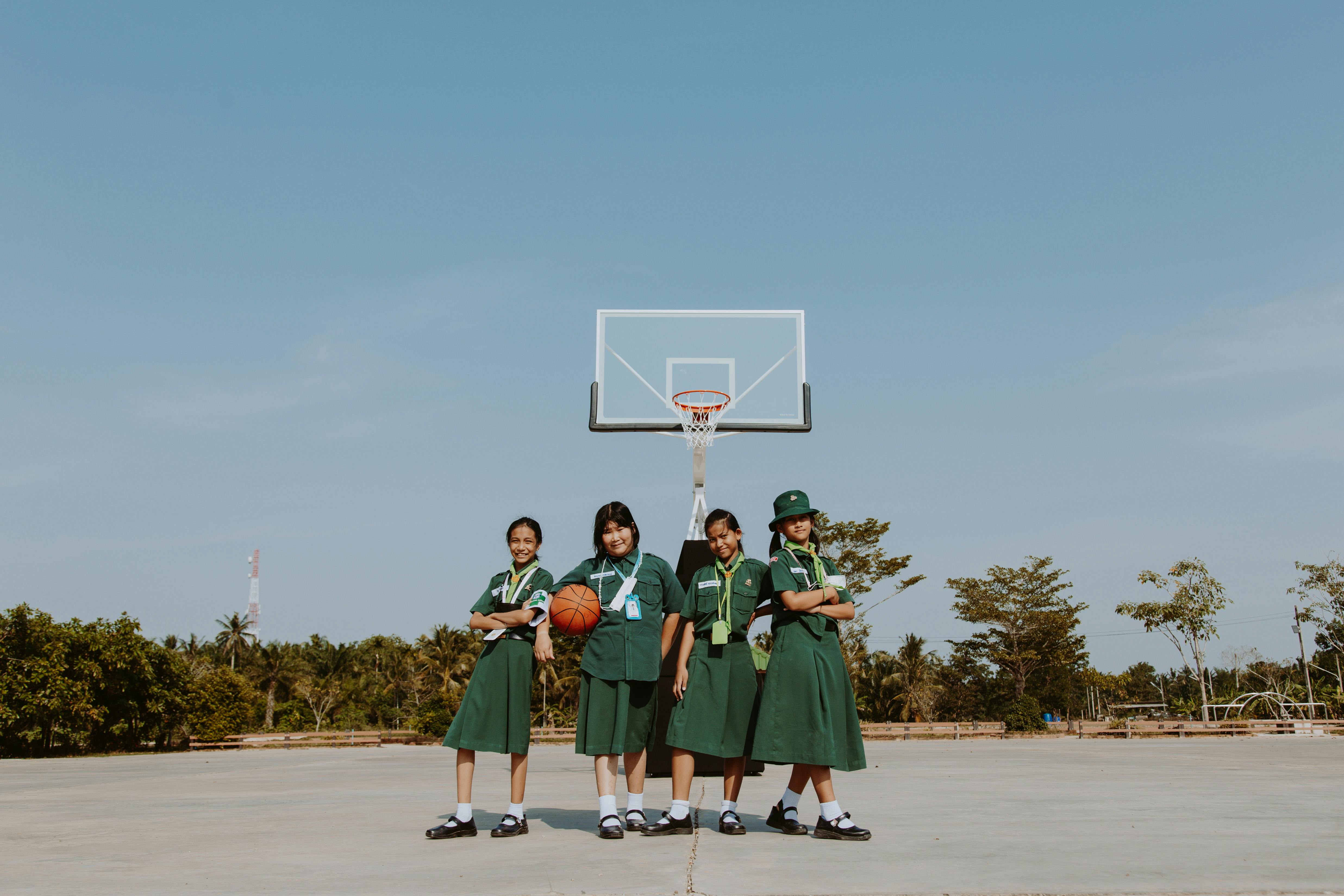 girls basketball team in school uniforms standing on court