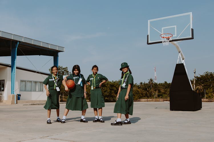 Girls Basketball Team In School Uniforms Standing On Court