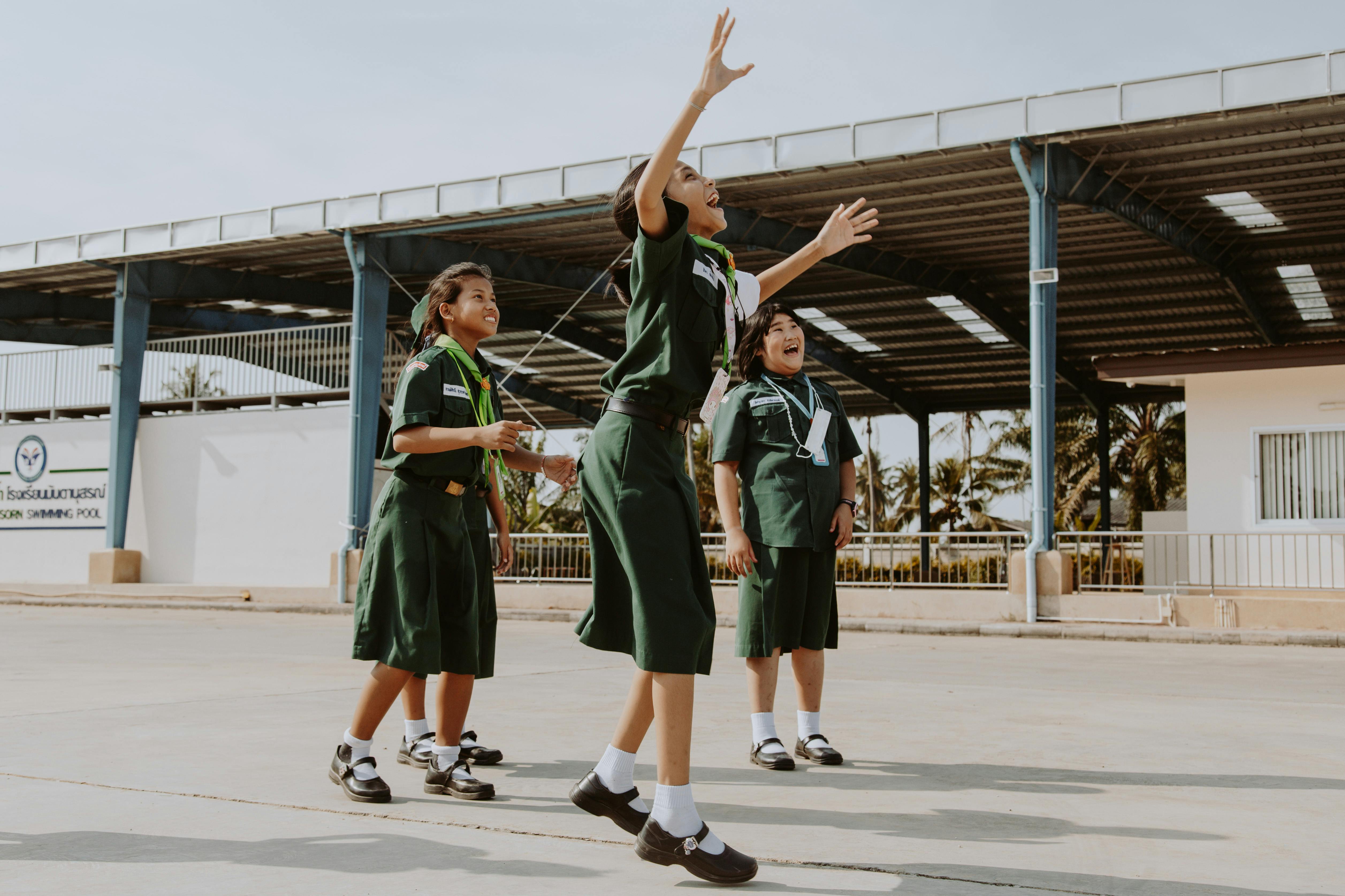 A group of cheerful girl scouts in uniform enjoying an outdoor activity under clear skies.