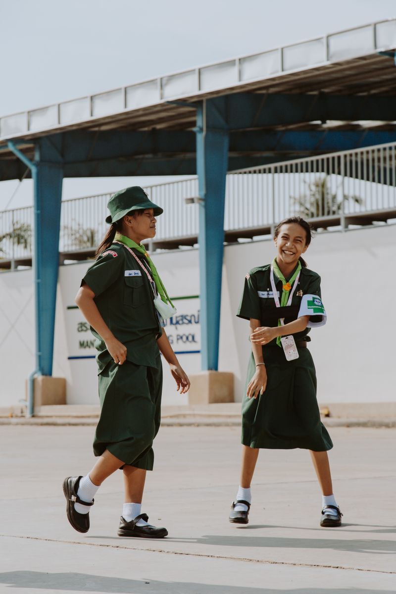 Two teen girls in uniform laughing together outdoors