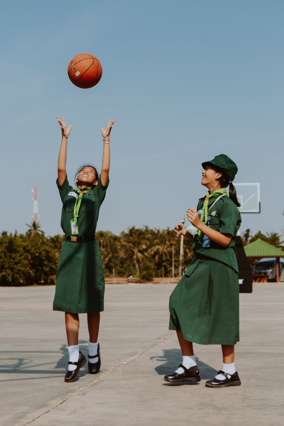Two students in uniform playing basketball on the school court