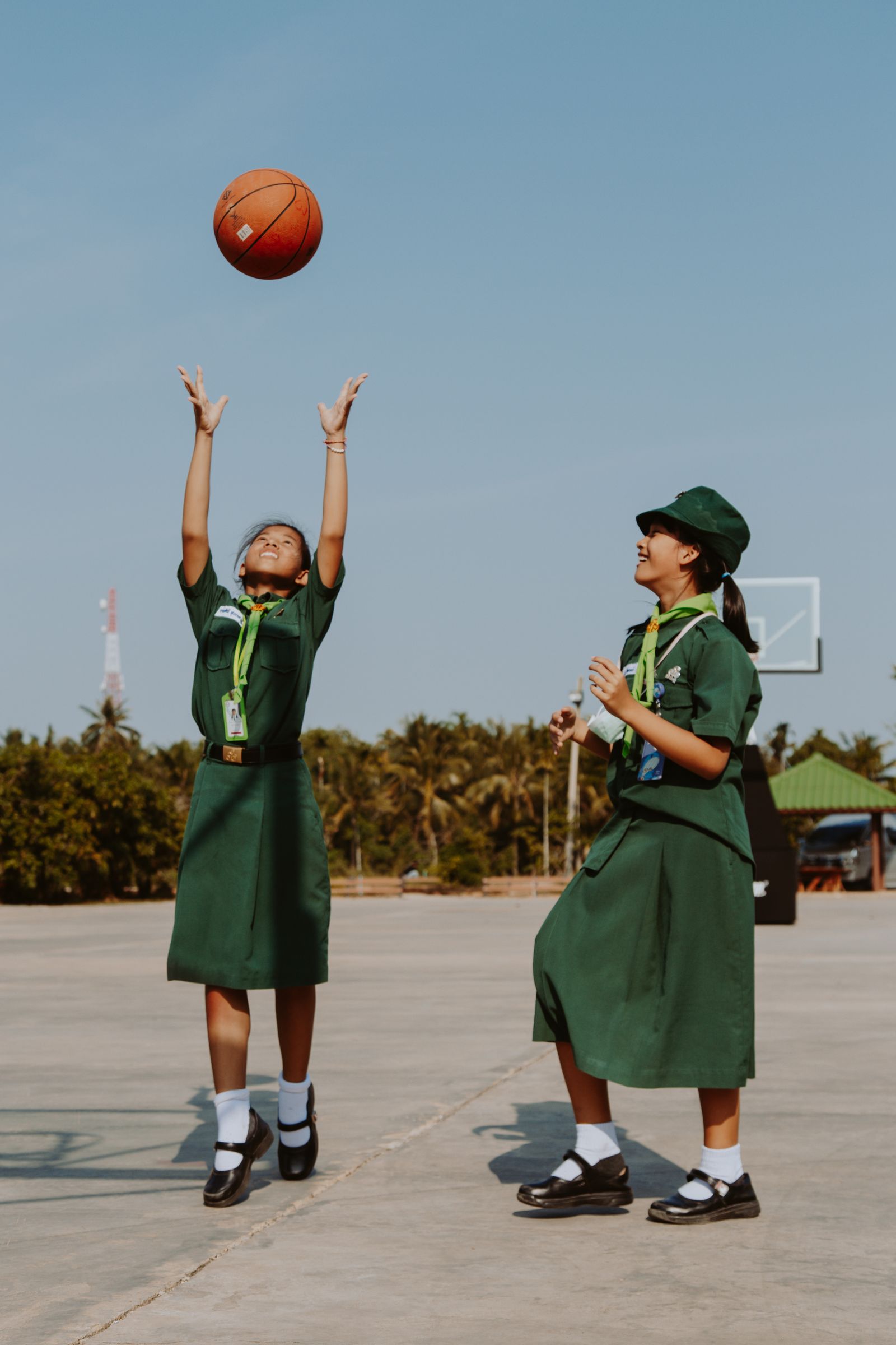 Two students playing basketball on an outdoor school court