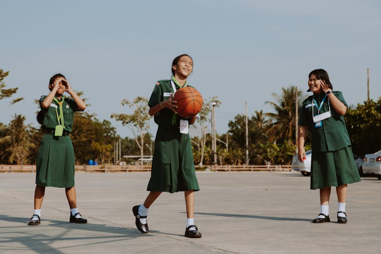 Girls In School Uniform Playing Basketball Outdoors