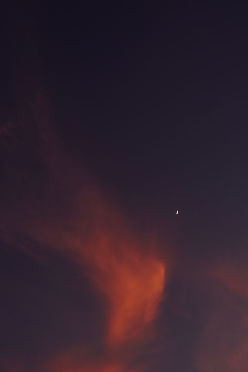 Free A stunning twilight sky with deep colors and a visible crescent moon amid swirling clouds. Stock Photo