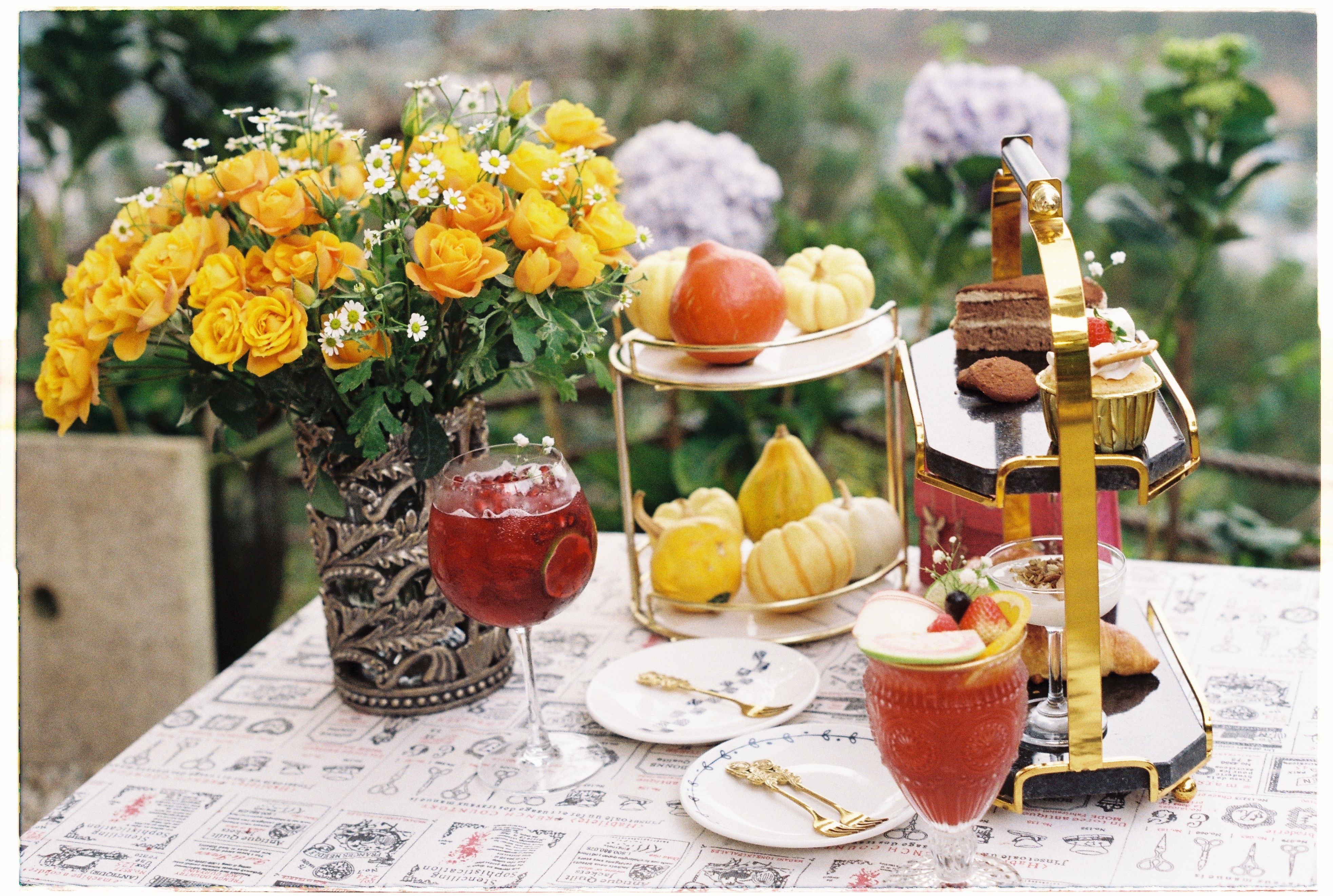 A stylish outdoor brunch setup with flowers, fruits, and refreshments on a decorated table.