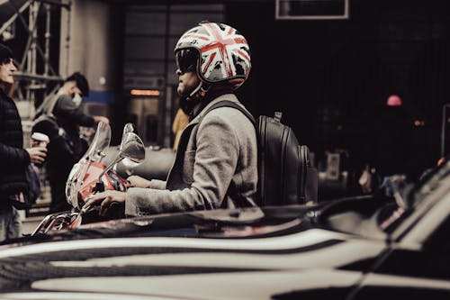 Free A Man in Gray Jacket Wearing Black Helmet while Riding on a Motorcycle Stock Photo