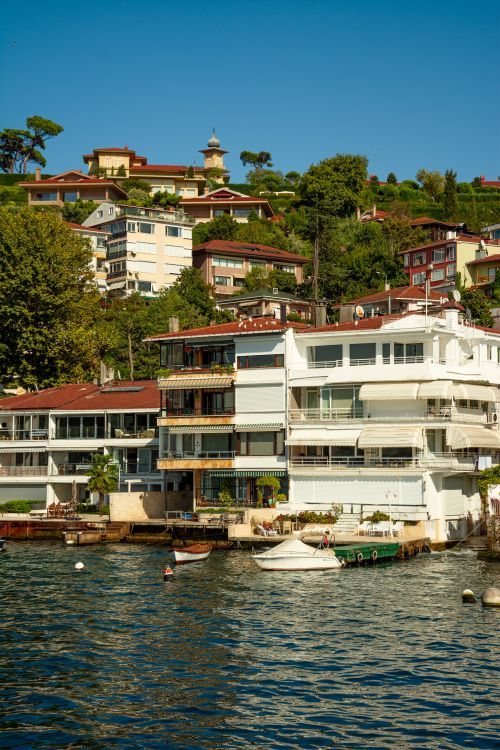 Free Idyllic waterfront view with modern homes and a boat dock nestled on a green hillside. Stock Photo