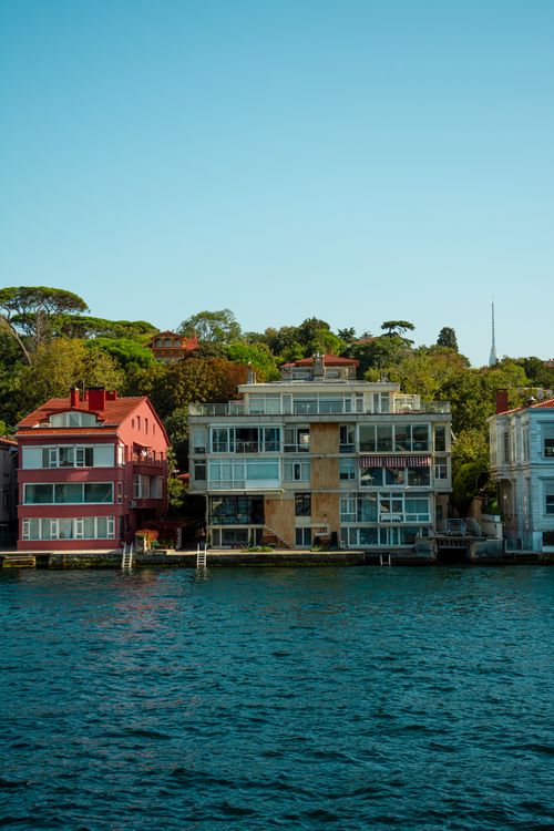 Free Scenic view of stylish waterfront houses with clear sunny sky and lush greenery. Stock Photo