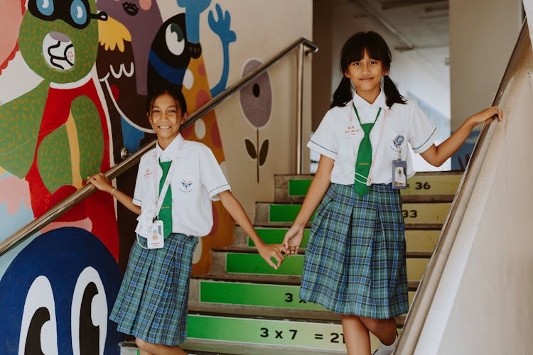 Two Girl Students In School Uniform Walking Down Stairs