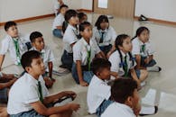 Children in School Uniforms Sitting on Floor in Classroom
