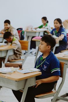 Students attentively listening during a class session in a brightly lit classroom. 10646424