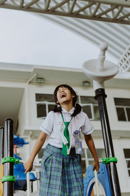 Free A happy schoolgirl in uniform enjoying playtime outdoors in a school playground. Stock Photo