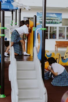 Kids in uniforms enjoying playtime on indoor playground at a school gymnasium.