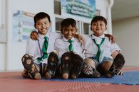 Portrait of Smiling Boys in School Uniforms Sitting on Floor