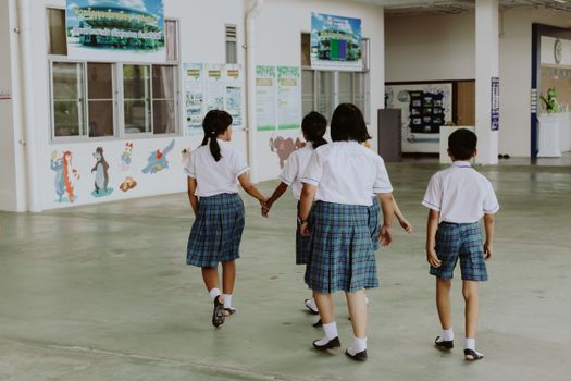 Children in school uniforms walking together indoors, depicting educational environment.