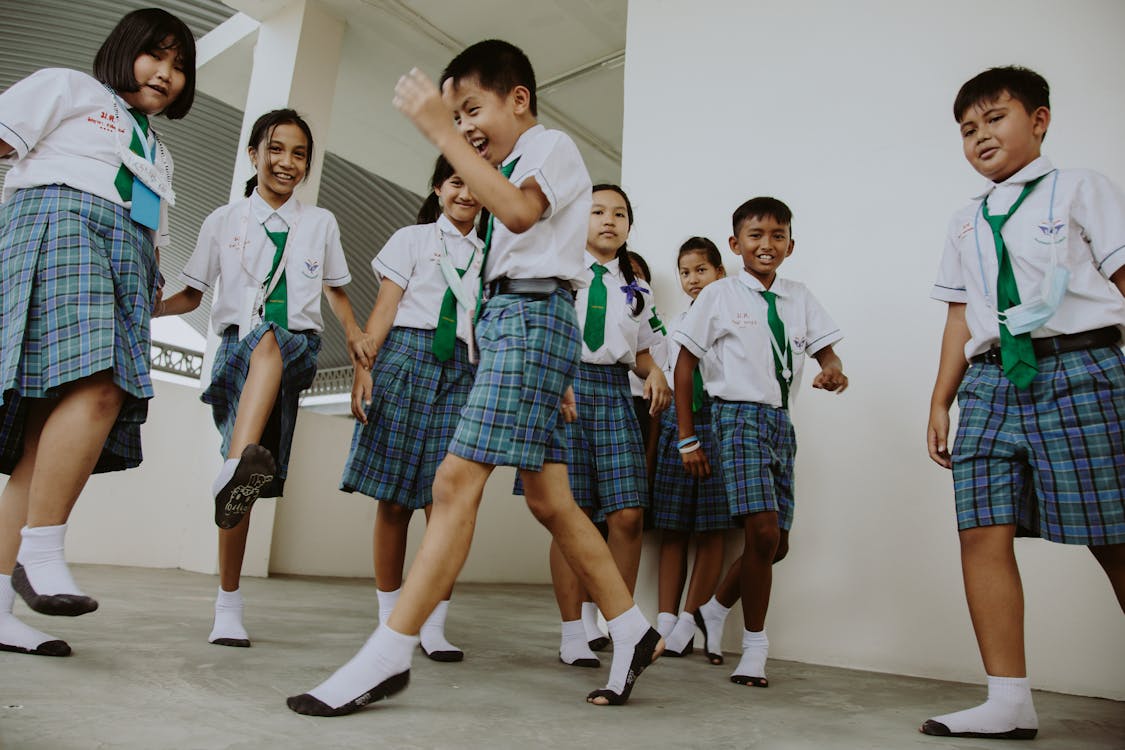 Free Smiling Boys and Girls in School Uniforms Playing in School Gymnasium Stock Photo