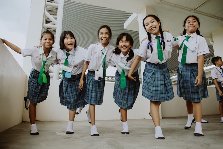 Young Girls Embracing While Standing On School Corridor
