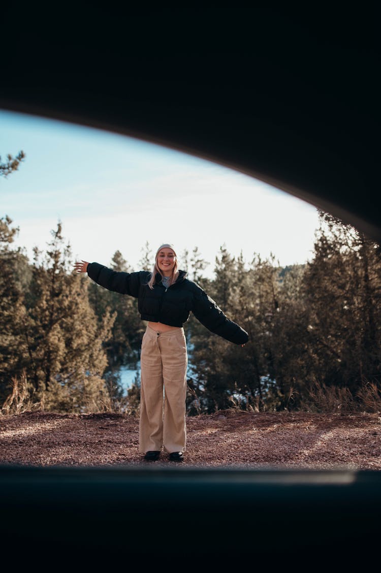 Smiling Woman Standing In Landscape Seen Through Car Window