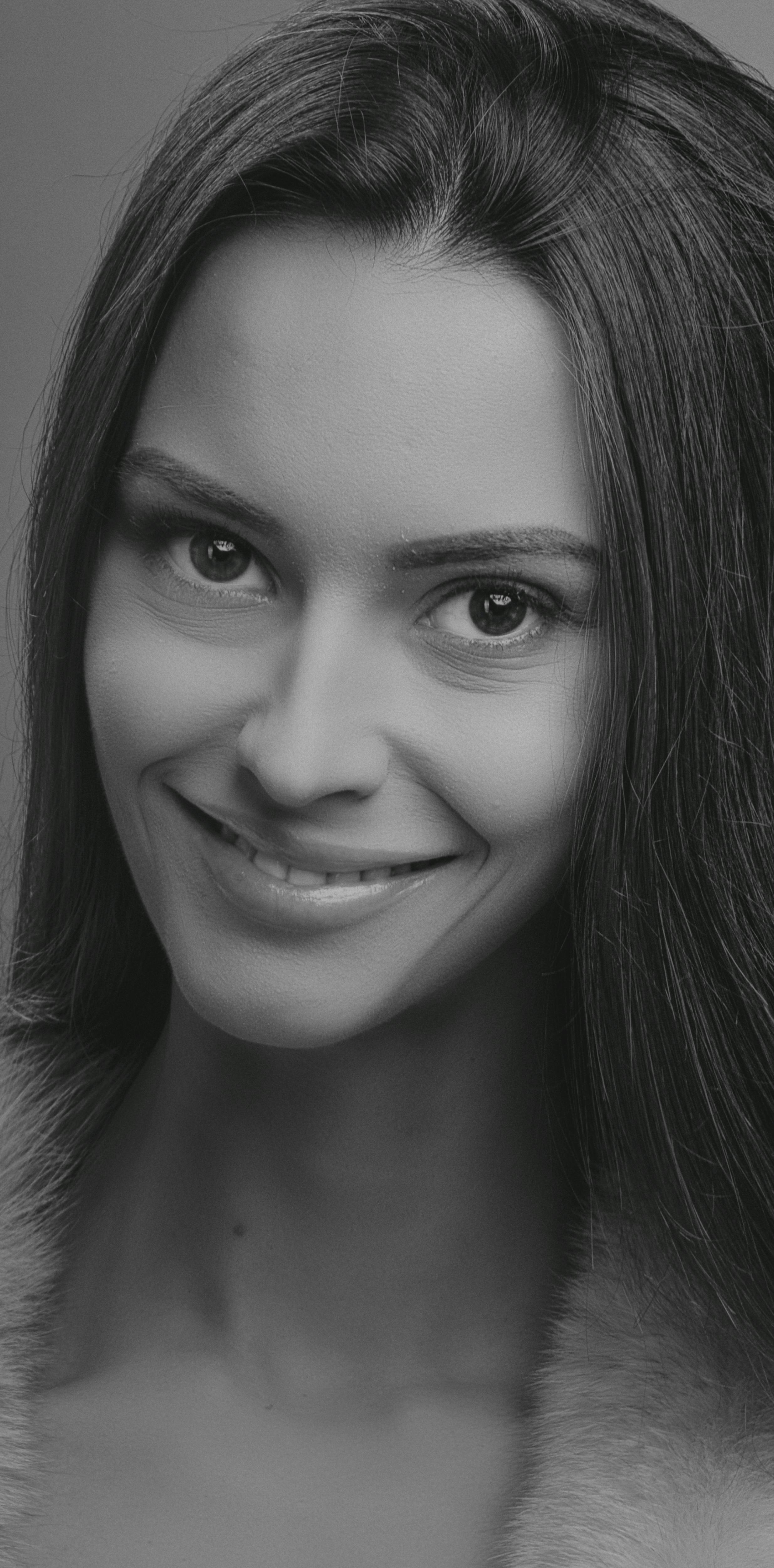 Black and white studio portrait of a smiling woman with long hair, conveying elegance and beauty.
