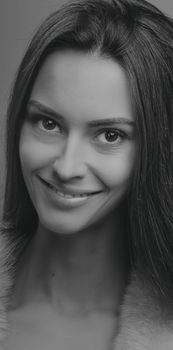 Black and white studio portrait of a smiling woman with long hair, conveying elegance and beauty.
