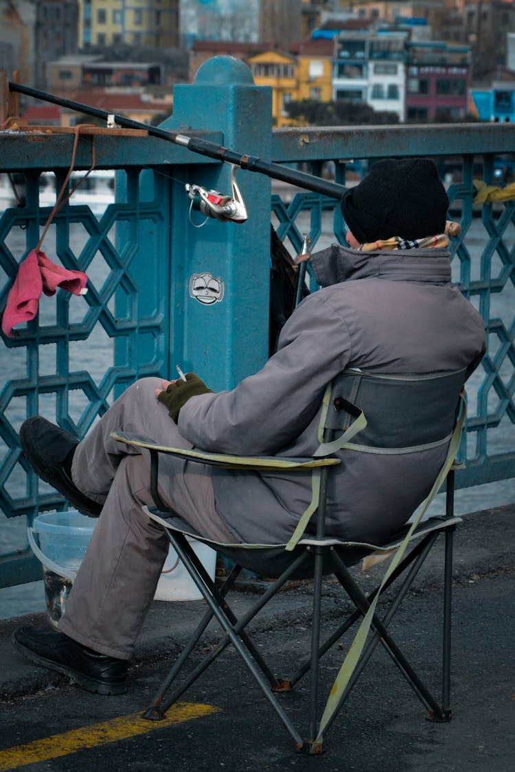 Old Man With Rod Fishing On Bridge