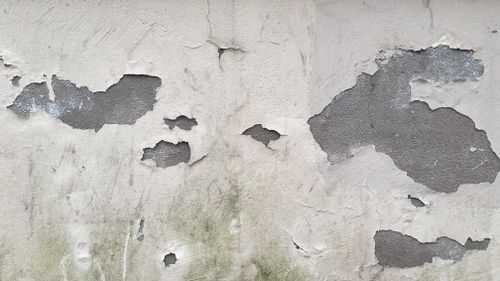 Free Close-up of an aged concrete wall with peeling paint and cracked surface, rich in texture. Stock Photo