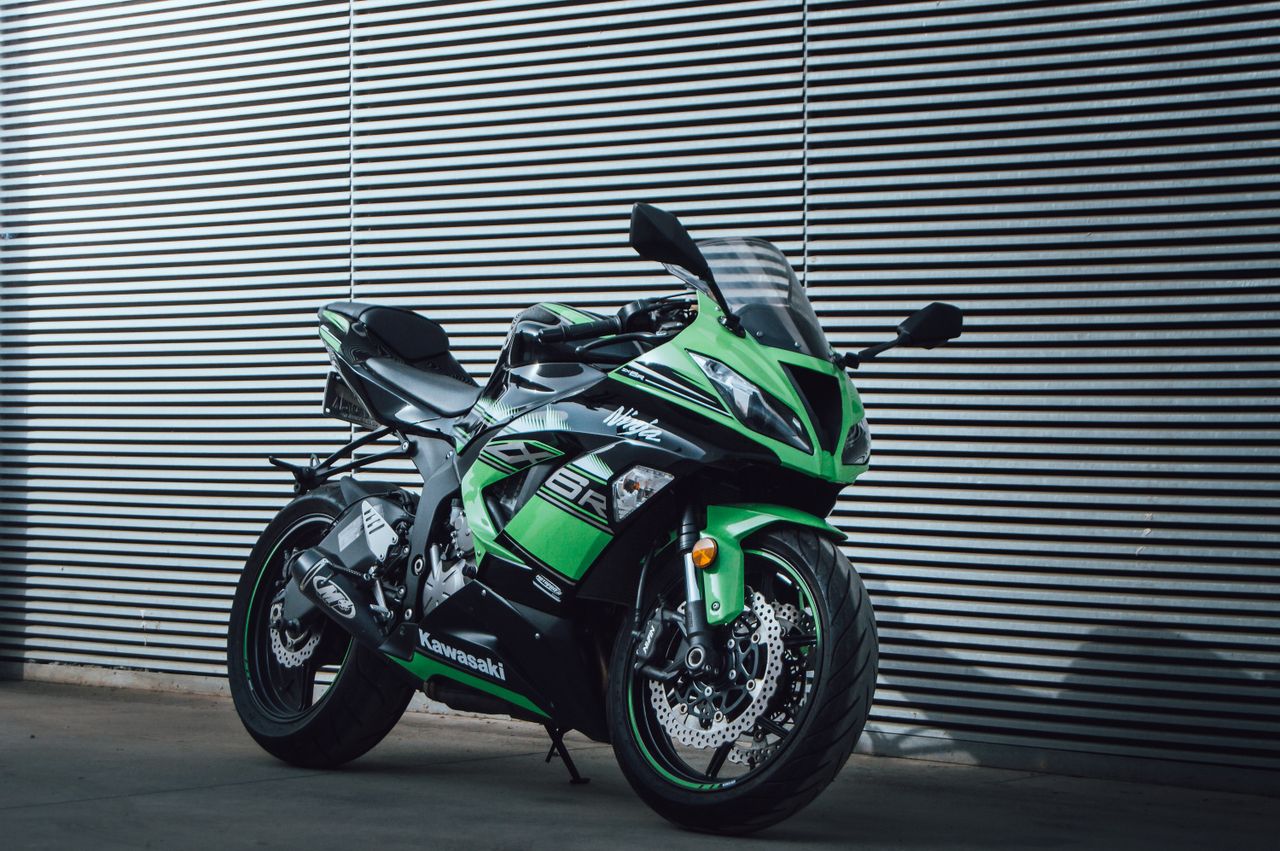 a vibrant green kawasaki ninja motorcycle parked outdoors against a mo