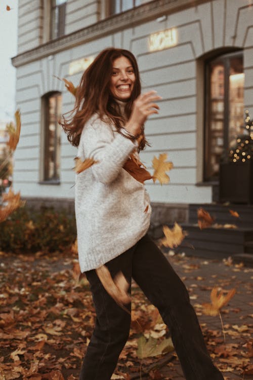 A Woman in Sweater and Black Pants while Smiling