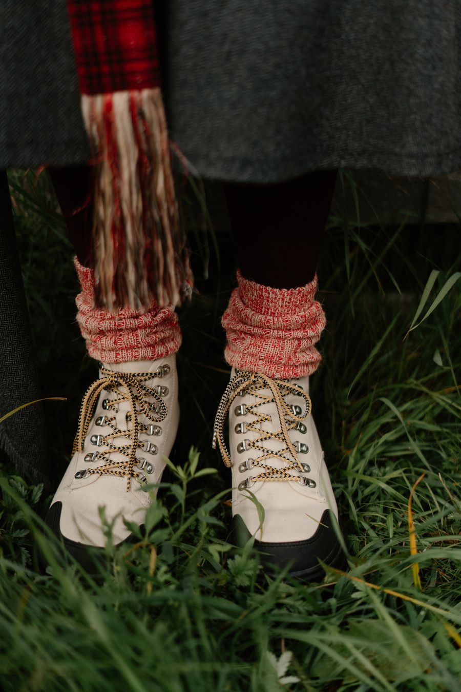Close-up of hiking boots with knit socks in grassy outdoors, evoking cozy autumn vibes. Stock Photo