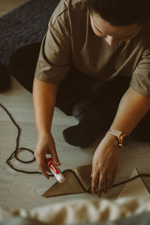 Free Woman engaged in crafting a DIY string art project on the floor with glue and paper. Stock Photo