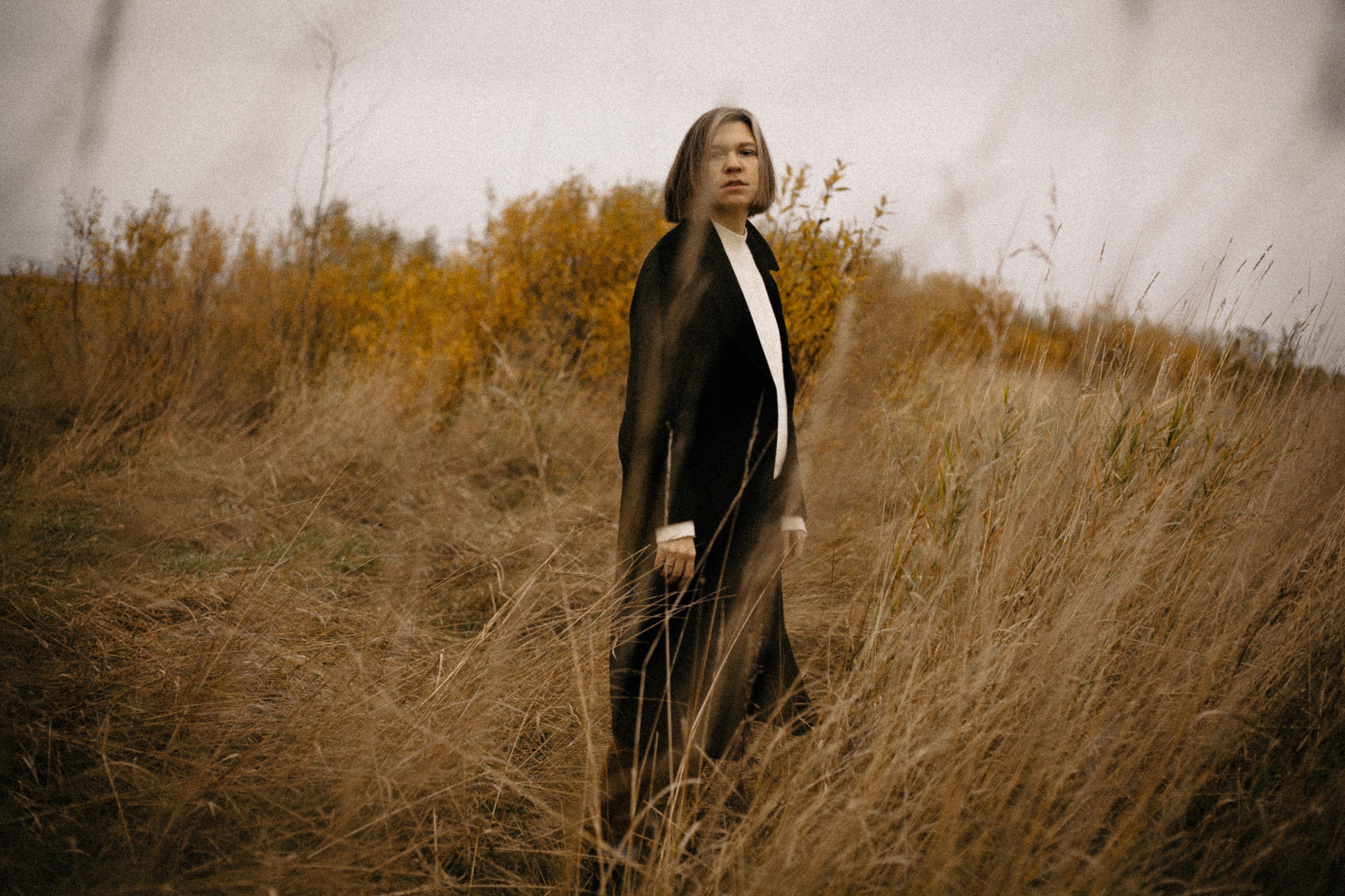 A Woman in Black Coat Standing on Brown Grass Field · Free Stock Photo