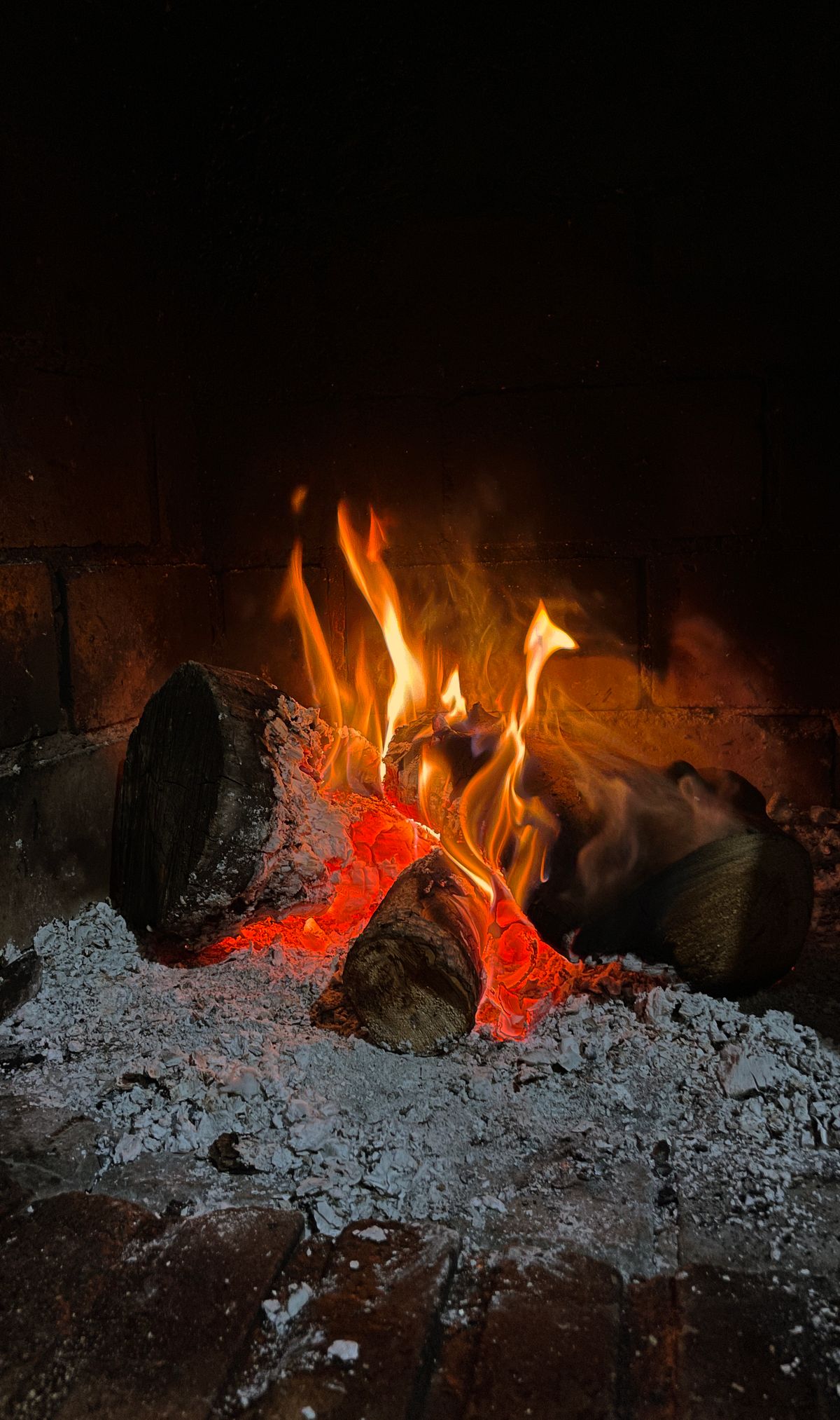 [Bild eines gemütlichen Kamins mit loderndem Feuer]