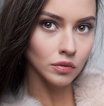 Close-up portrait of a young woman with soft lighting and neutral tones.