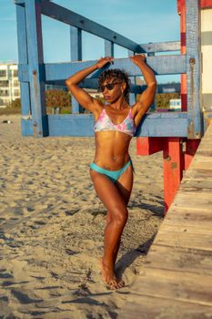 Confident woman in a swimsuit posing by a colorful lifeguard station on a sunny Cocoa Beach.