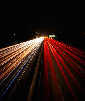 An urban highway captured with long exposure, showing dynamic light streaks from vehicles at night.