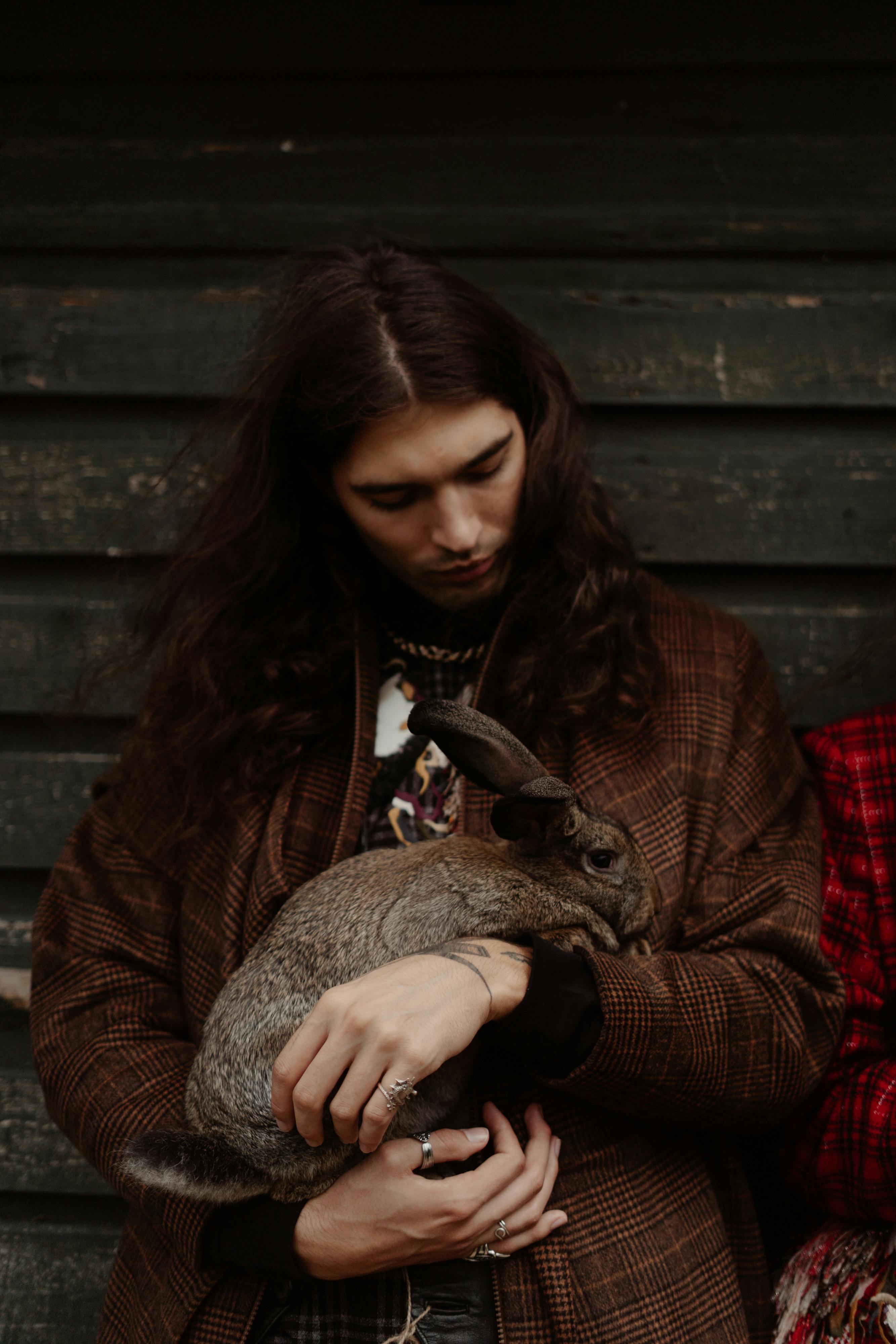 man with long hair holding a rabbit