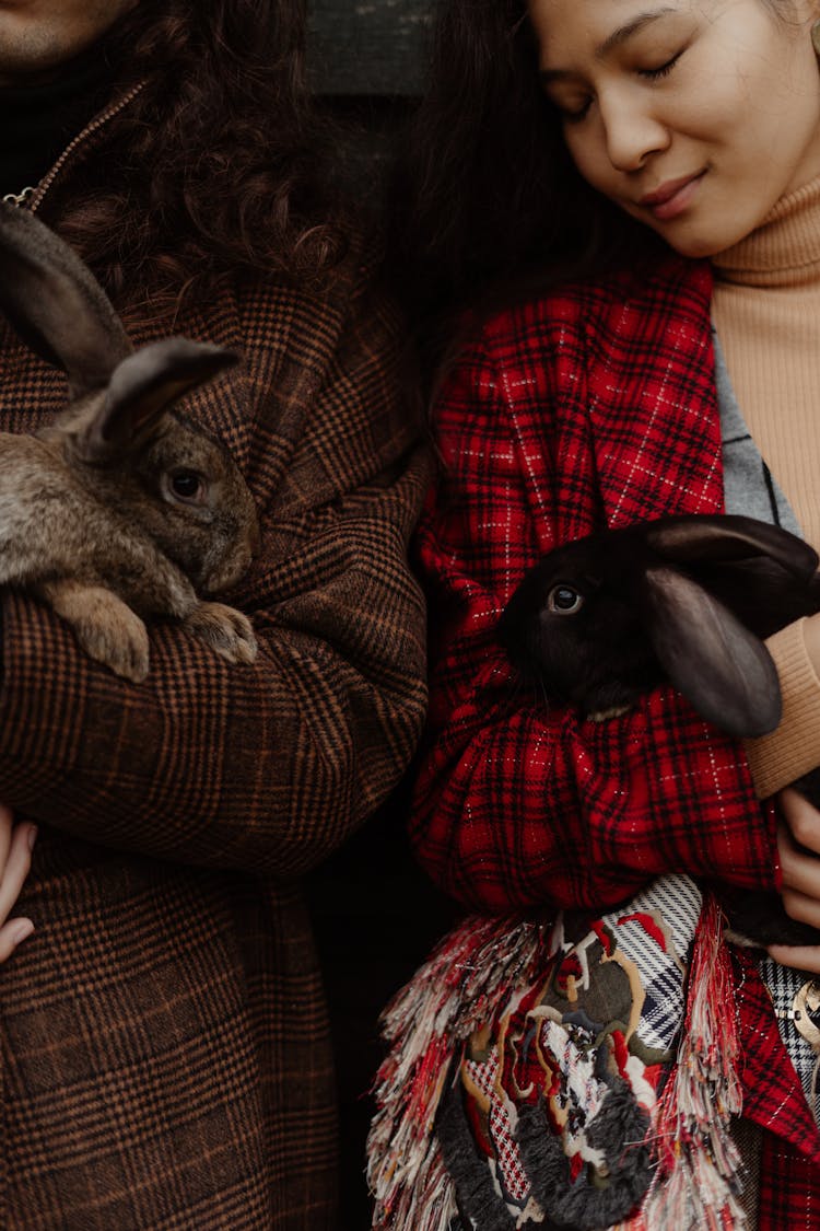 People Carrying A Black And Brown Rabbits 